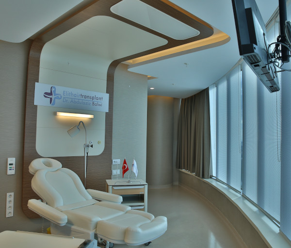 Salle de traitement avec fauteuil inclinable et télévision dans la clinique du cheveux d'Istanbul