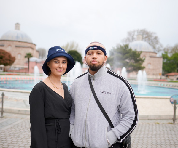 Un couple pose devant une fontaine après que chacun ait fait sa greffe de cheveux percutanée en Turquie