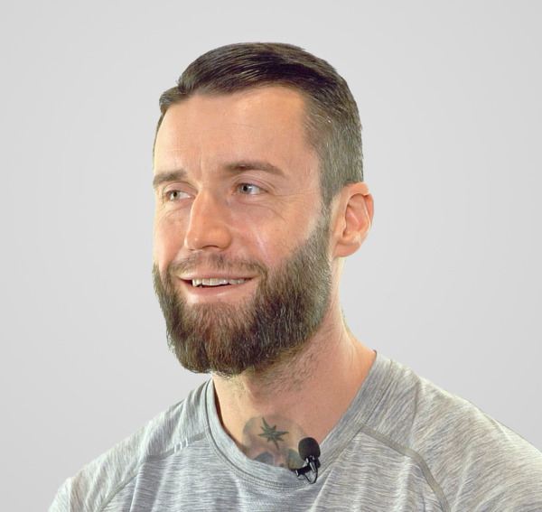 Un homme à la barbe fournie sourit