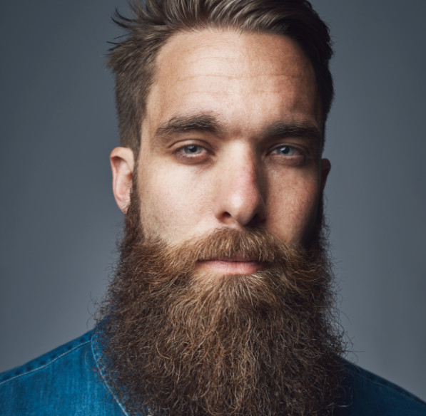 Un homme à la barbe restaurée regarde l'appareil photo
