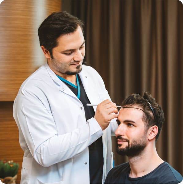 le Dr Balwi ausculte le cuir chevelu et dessine la nouvelle ligne capillaire d'un patient avant sa greffe de cheveux chez Elithair