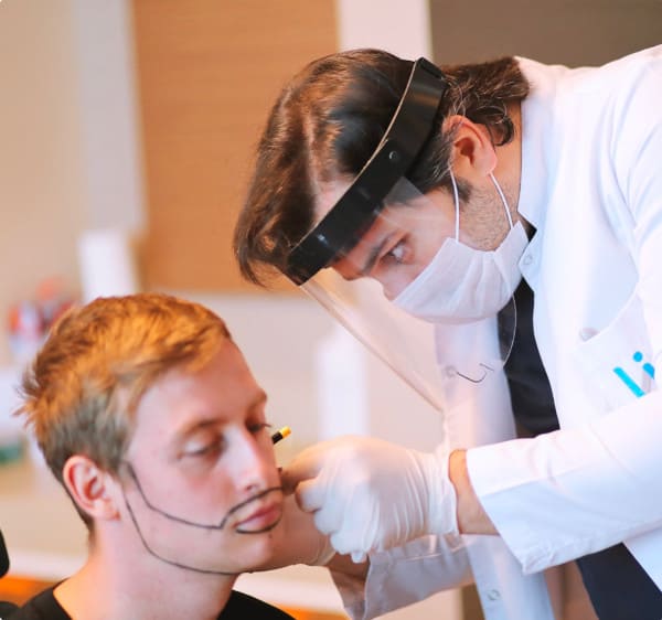 le dr balwi examinant un patient pour une greffe de barbe
