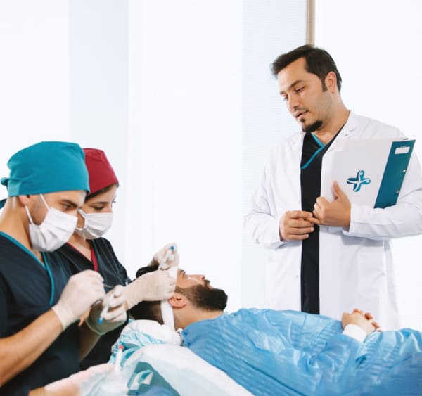 Dr. Balwi discutant avec un patient pendant une greffe de cheveux DHI