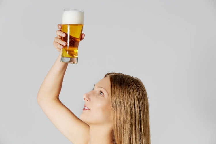 Frau hält sich ein Glas Bier über die Haare