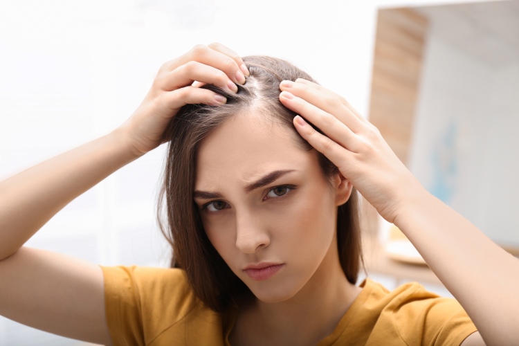 Frau untersucht Ihre Haare auf zyklusbedingten Haarausfall