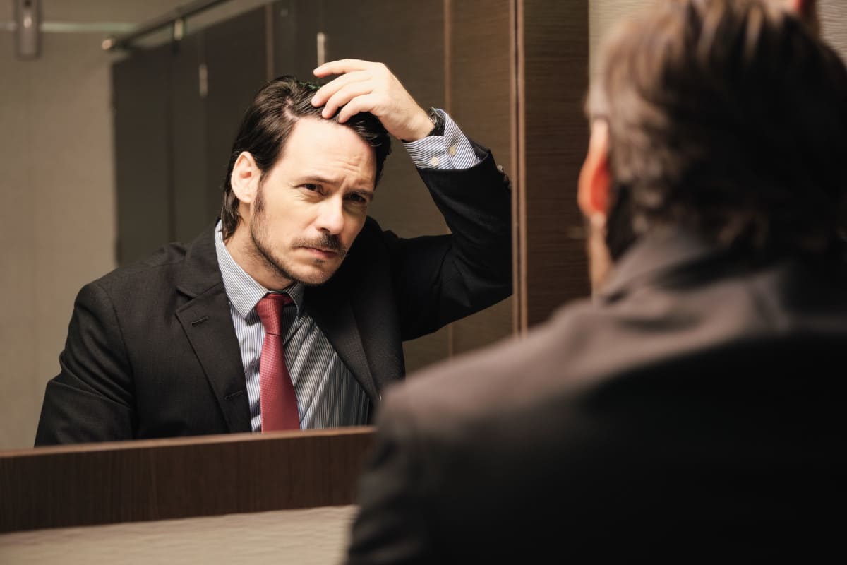 Haarausfall vorbeugen - Mann vor dem Spiegel