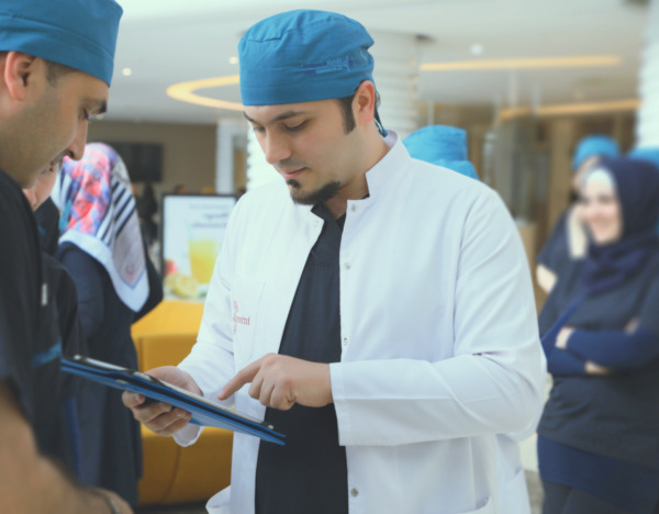 Dr. Balwi mit Kollegen am Tablet liest Artikel über DHI Haartransplantation