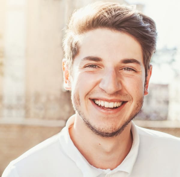 Junger Mann mit begeistertem Lächeln nach Haartransplantation in Wien