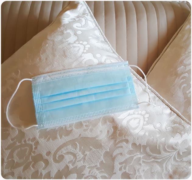 Nahaufnahme es desinfizierten Hotelbetts mit Mundschutzmasken auf den Kissen