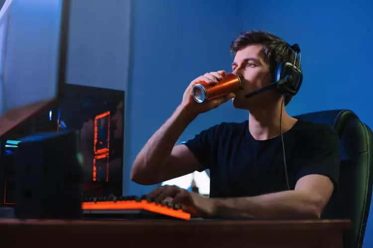 Streamer sitzt vor einem PC und trinkt einen Energydrink