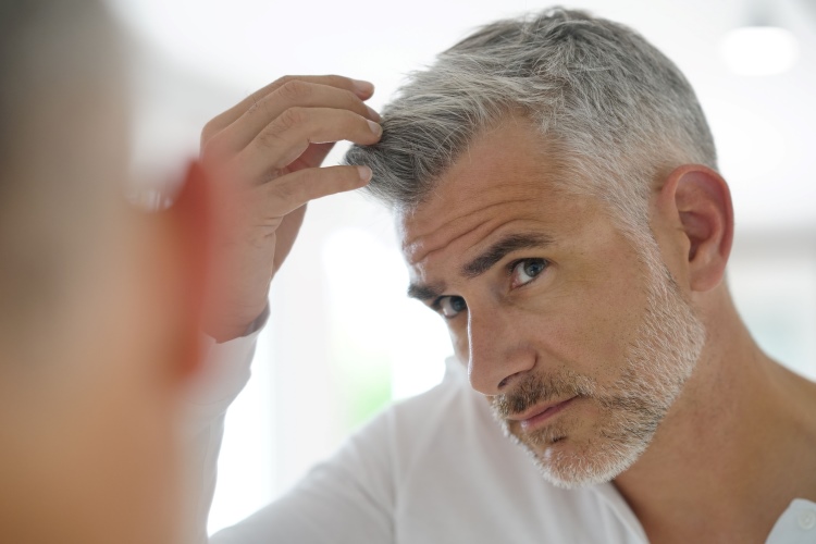 Mann mit grauen Haaren vor dem Spiegel