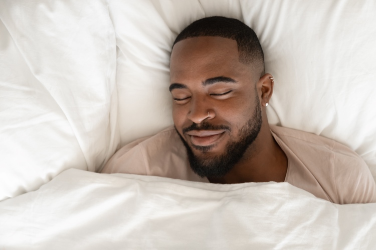 Mann schläft in einem Bett und sieht glücklich aus