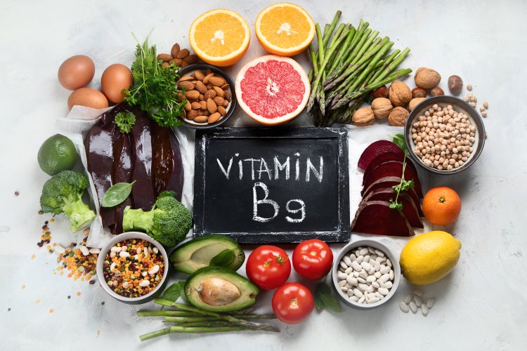 Lebensmittel die Folsäure enthalten liegen um ein Schild auf dem Vitamin B9 steht