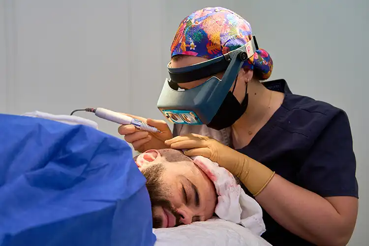 Ein Mann liegt im OP-Saal, bei ihm wird eine Haartransplantation durchgeführt