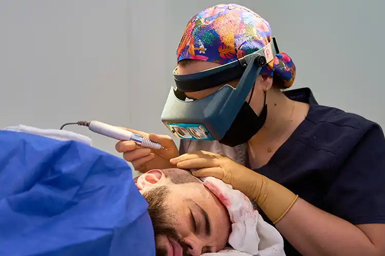 Ein Mann liegt im OP-Saal, bei ihm wird eine Haartransplantation durchgeführt