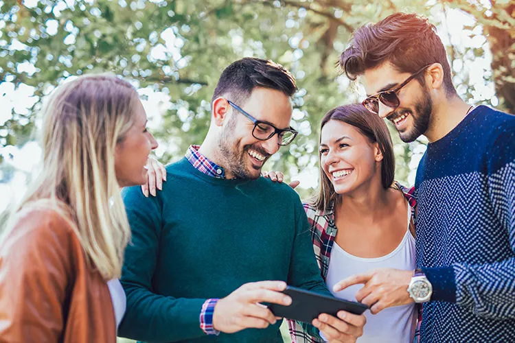 Vier Freunde schauen gemeinsam auf ein handy und lachen