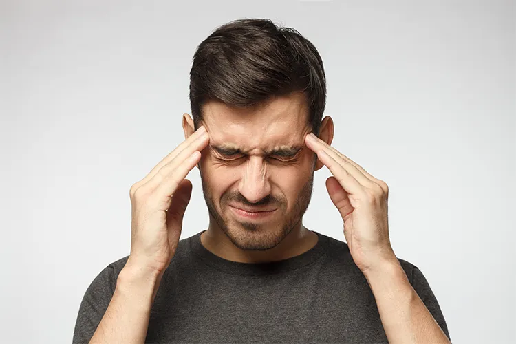 Mann mit schmerzverzerrtem Gesicht und Händen am Kopf – steht für Stress, Kopfhautverspannung und nervlich bedingte Beschwerden
