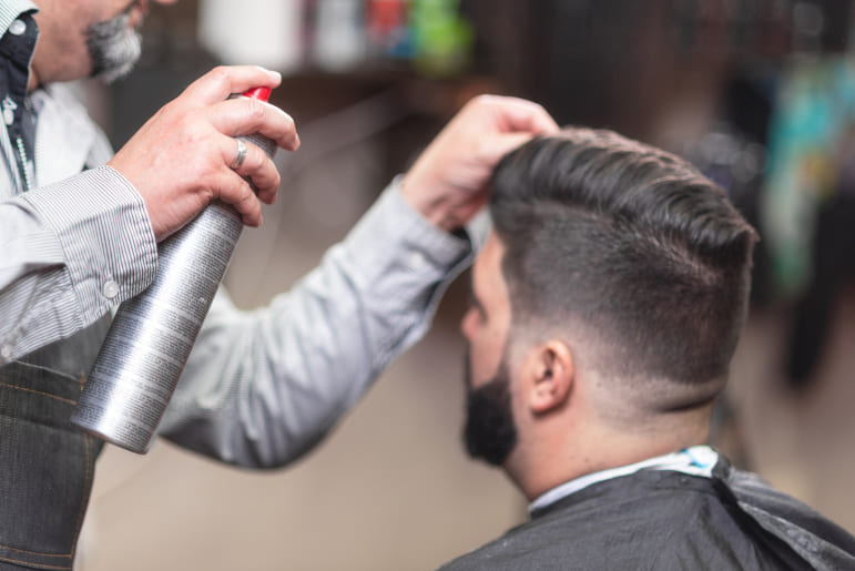 Haarausfall kann durch Haarspray verursacht werden Mann beim Friseur wird mit Haarspray gestyled