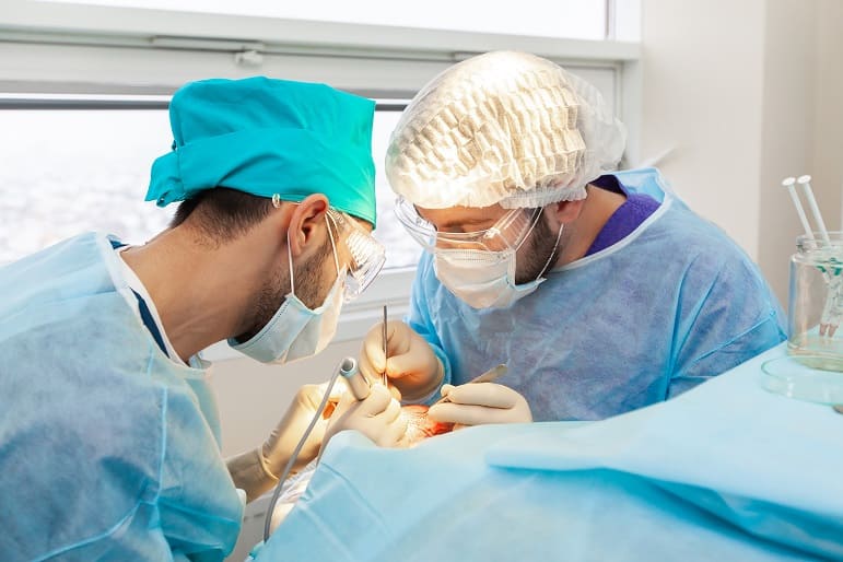 Zwei Ärzte nehmen eine Haartransplantation bei einem Patienten vor