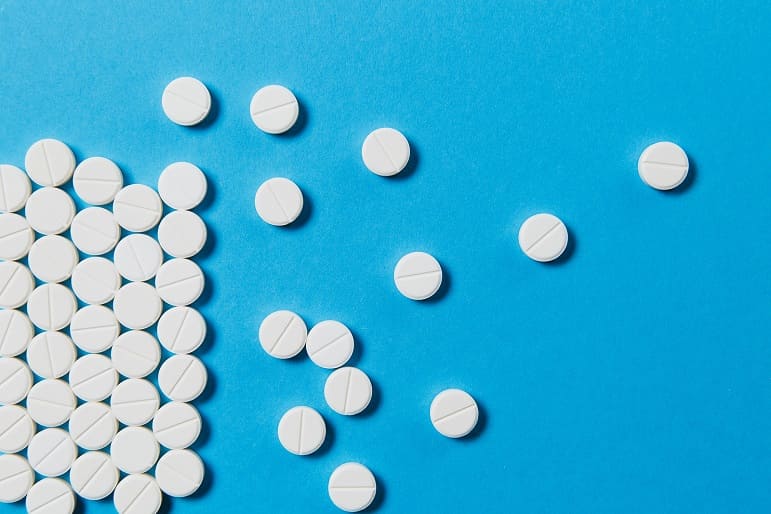 Viele weiße Tabletten liegend auf blauen Hintergrund