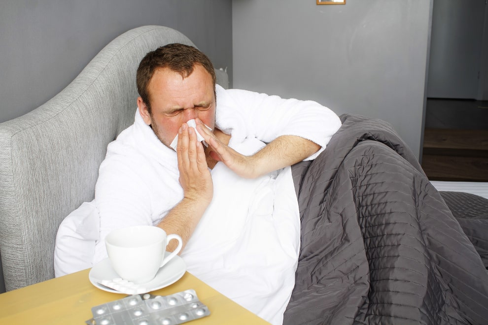 Mann liegt im Bett mit Haarausfall nach Grippe