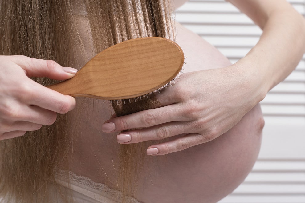 Frau bürstet Ihre Haare bei Haarausfall in der Schwangerschaft