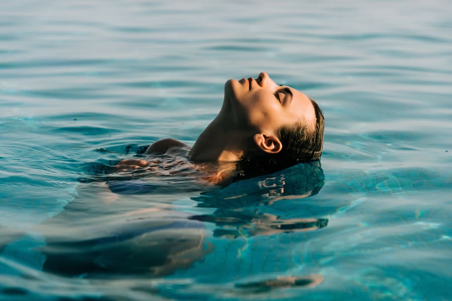 una donna mentre bagna i suoi capelli in acqua a mare