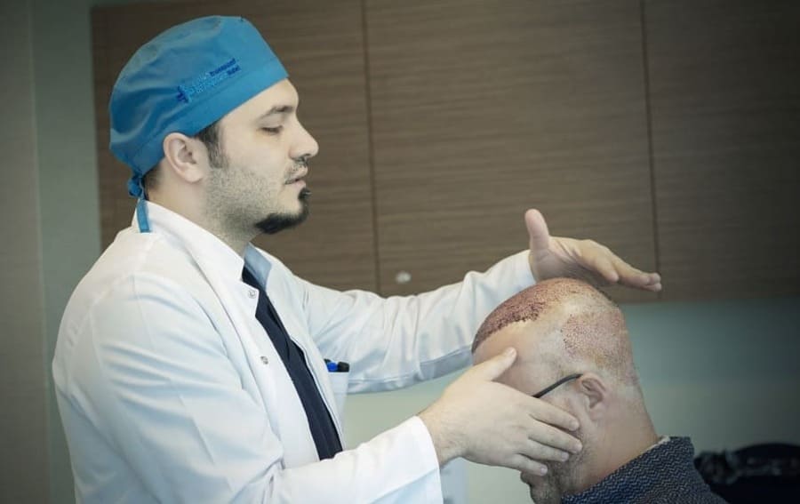 il dr balwi controlla le crosticine dopo il trapianto di capelli di un paziente