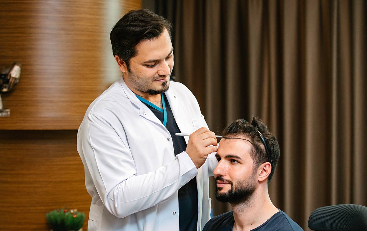 Il Dr. Balwi disegna la nuova attaccatura dei capelli trapiantati di un paziente