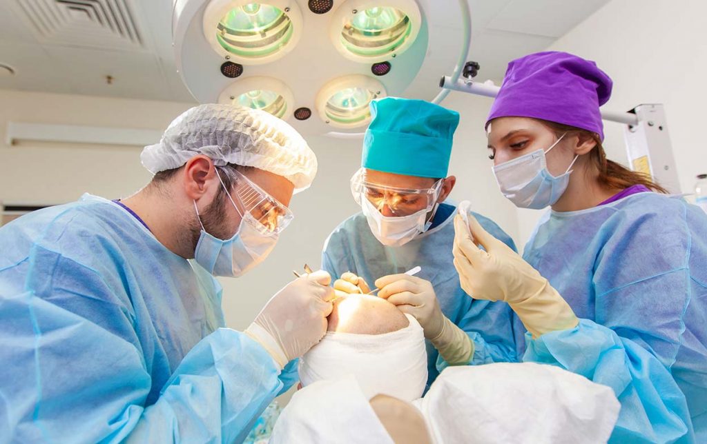 Equipa médica na sala de operações durante a operação de transplante percutâneo de cabelo