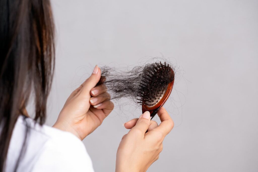 Mujer revisando el problema de alopecia que sufre en un cepillo lleno de pelo