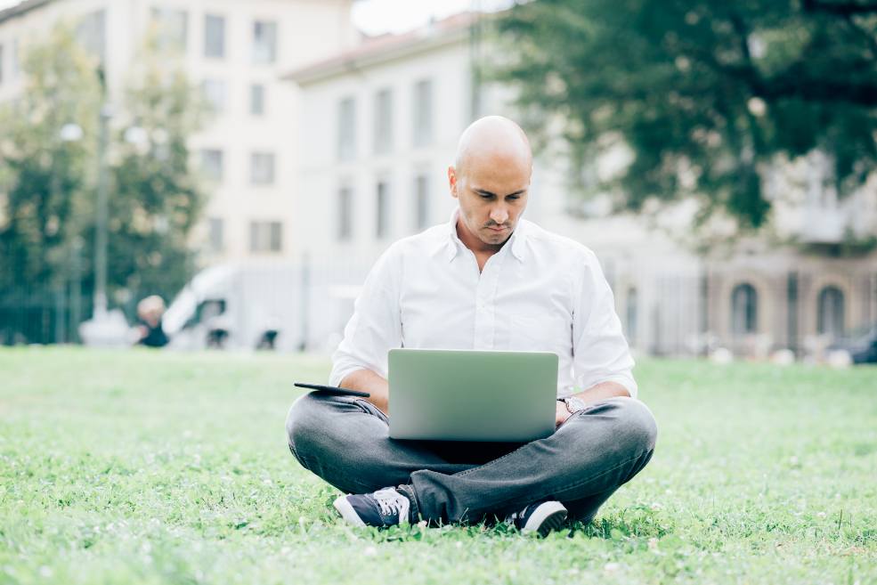 Hombre calvo leyendo en un ordenador en el parque