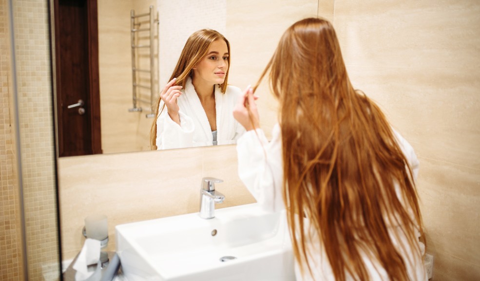Mujer inspecciona su cabello frente al espejo
