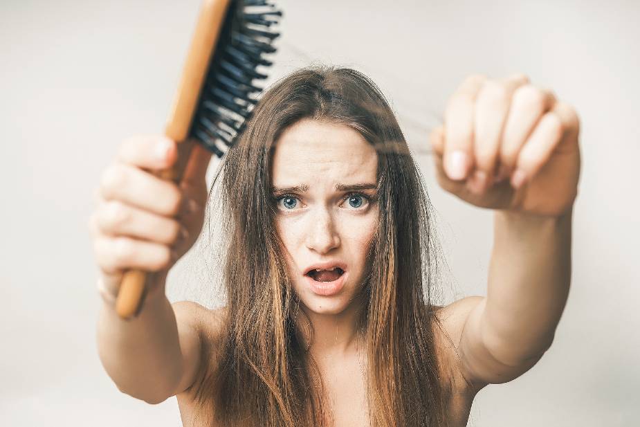 Mujer observando el cabello enganchado en el cepillo