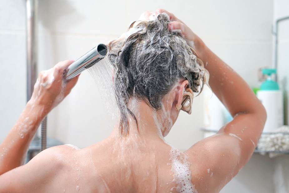 Mujer demostrando cómo lavarse el pelo correctamente en la ducha