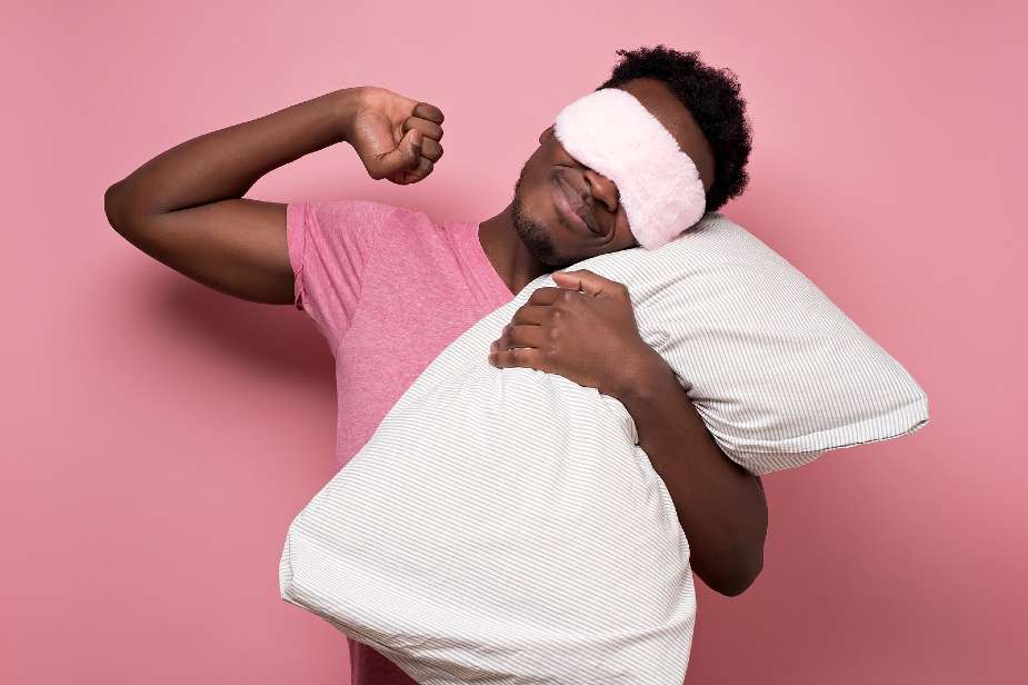 Hombre con máscara de dormir sujetando una almohada