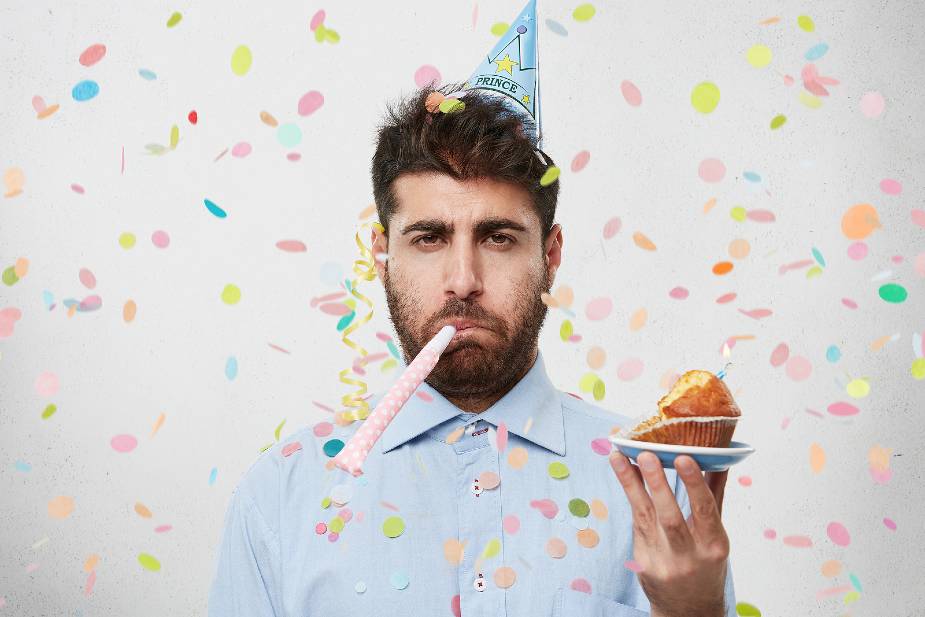 Hombre celebrando su cumpleaños con una madalena y confetti