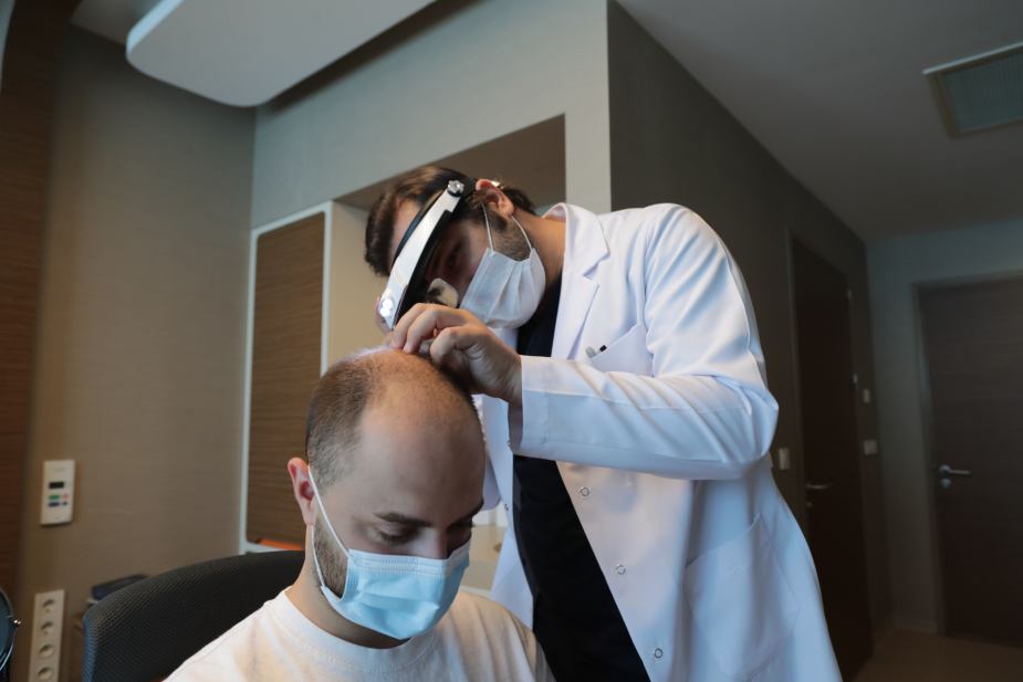 Dr. Balwi en la consulta con un paciente durante la cual se dibuja la línea frontal del pelo.