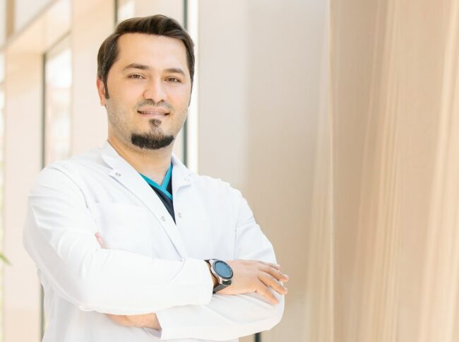 Imagen del Dr. Balwi sonriente con los brazos cruzados frente a la clínica