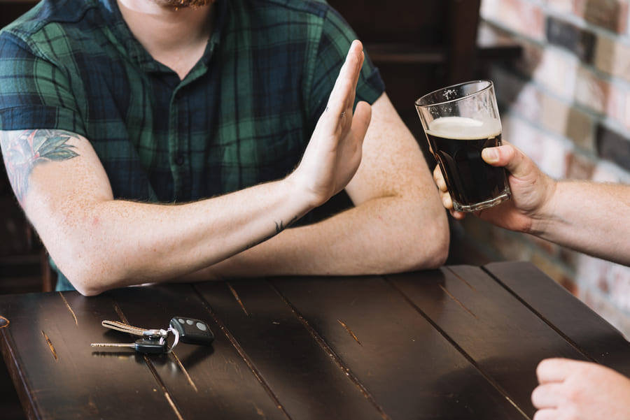 Hombre negando una bebida con alcohol después de su injerto capilar.