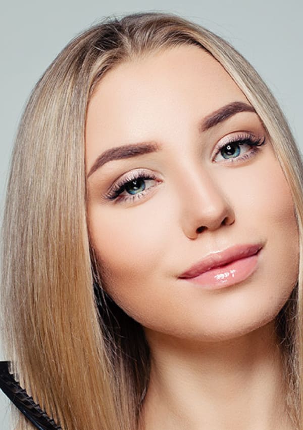Blonde woman combing her hair after a hair transplant