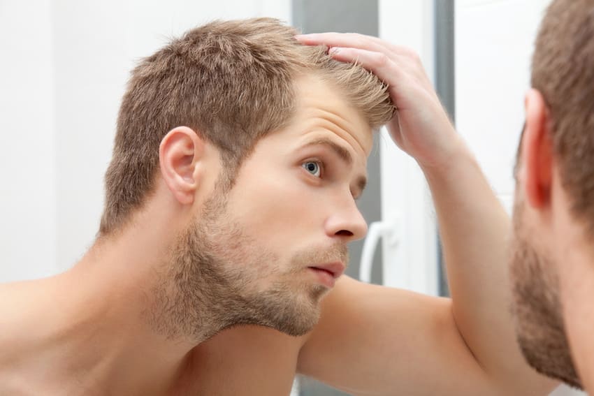 A man looking at the condition of his hair