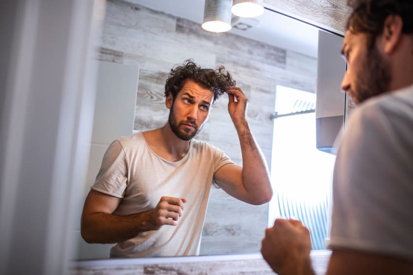Man applying hair care products to his hair at home